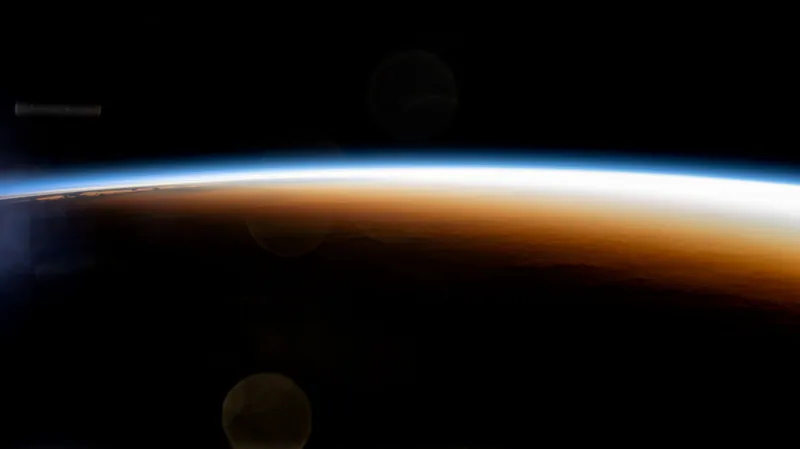 Un răsărit deasupra Pacificului fotografiat de pe stația spațială: un arc luminos de lumină de-a lungul orizontului curbat al Pământului